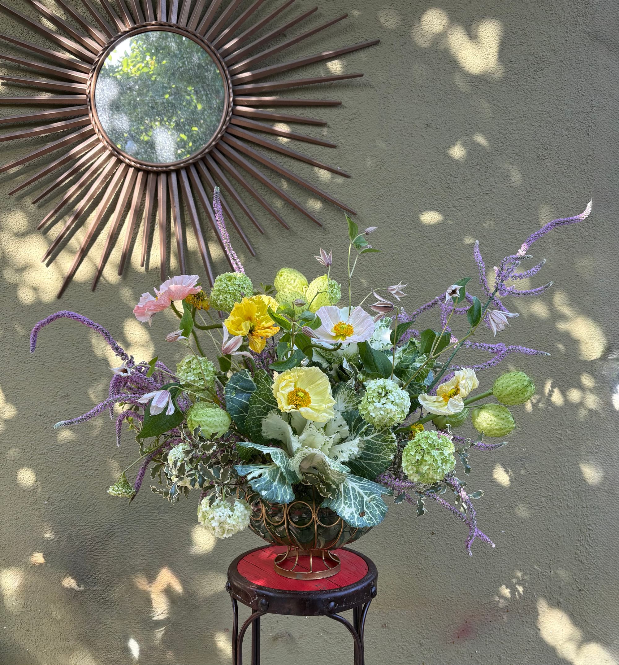 Butter-yellow poppies, viburnum and ornamental kale in dappled afternoon light